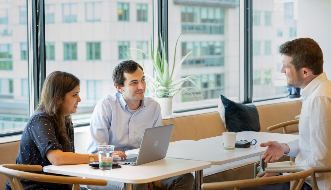 Three Ipsen Cambridge employees meet and collaborate in the office cafe.